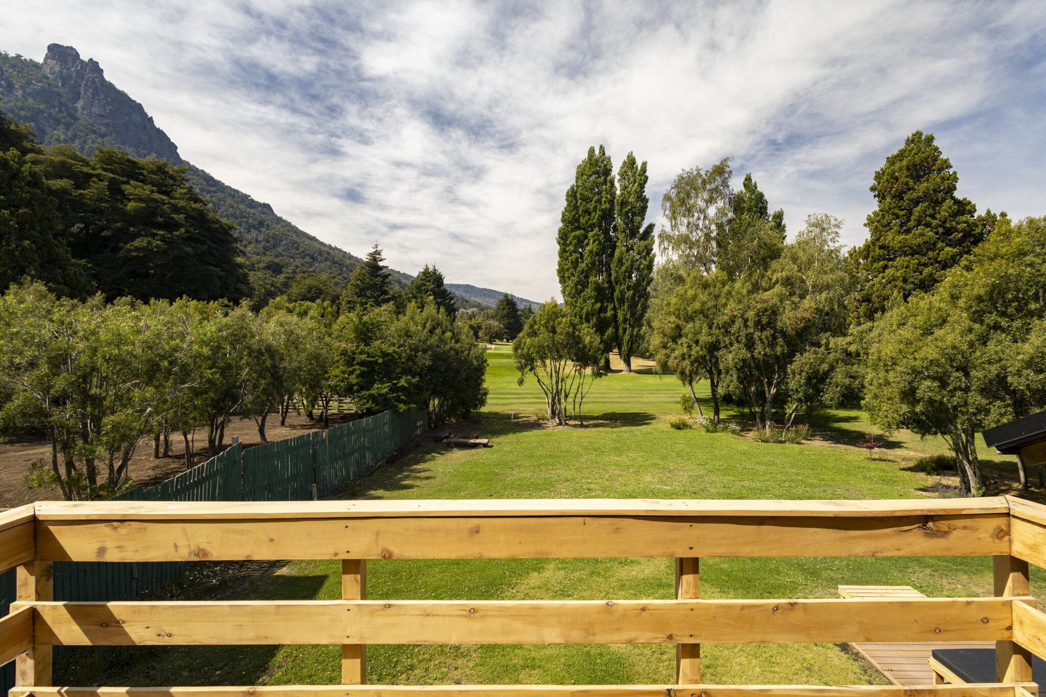 Mountain view from wooden deck with trees.